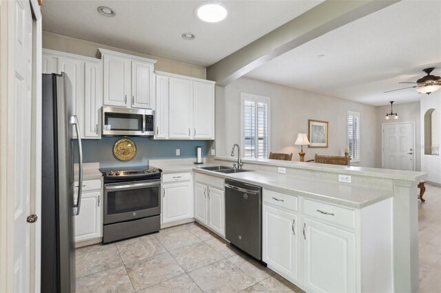 kitchen with white cabinetry, a sink, appliances with stainless steel finishes, and a peninsula