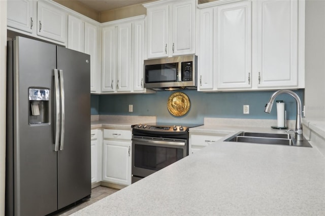 kitchen with light tile patterned flooring, light countertops, a sink, white cabinetry, and appliances with stainless steel finishes