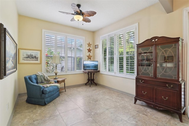 living area featuring light tile patterned flooring, baseboards, and a ceiling fan