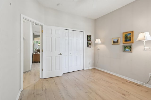 unfurnished bedroom with a closet, baseboards, and light wood-type flooring