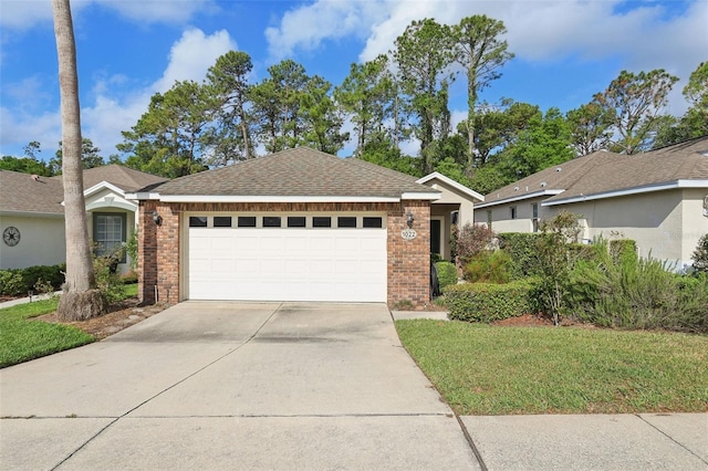 ranch-style house with a shingled roof, an attached garage, brick siding, and concrete driveway