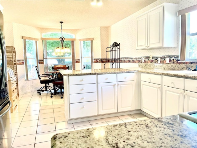 kitchen featuring wallpapered walls, a notable chandelier, and white cabinetry