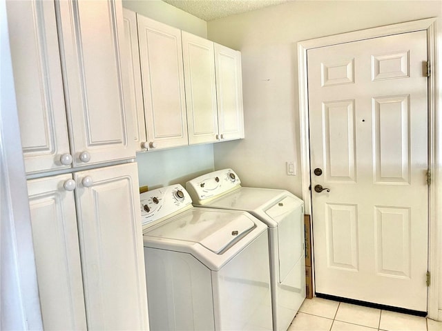 clothes washing area with washer and clothes dryer, a textured ceiling, cabinet space, and light tile patterned floors