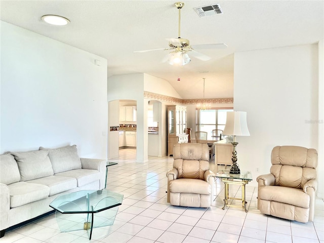 living area with light tile patterned flooring, vaulted ceiling, visible vents, arched walkways, and ceiling fan