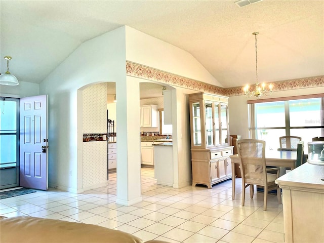 dining area with lofted ceiling, baseboards, a chandelier, light tile patterned flooring, and arched walkways