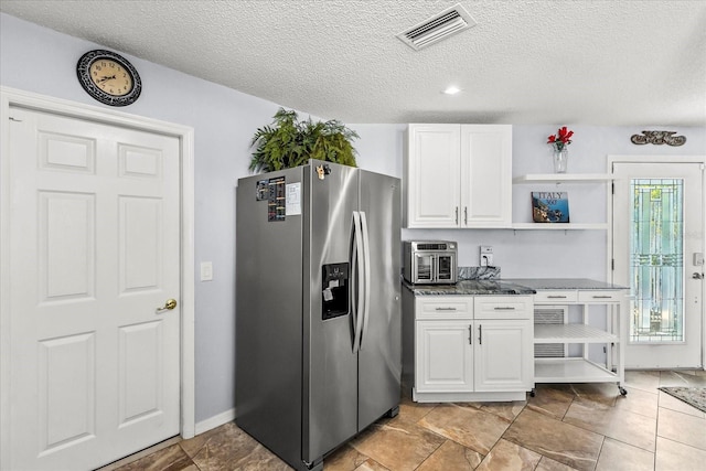 1917 Peachtree Ave, The Villages, FL 32162 - kitchen featuring stainless steel fridge, open shelves, white cabinetry, a textured ceiling, and dark stone counters