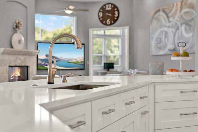 13112 Luntz Point Ln, Windermere, FL 34786 - kitchen featuring a sink, a premium fireplace, white cabinets, and light countertops