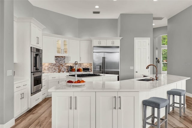 13112 Luntz Point Ln, Windermere, FL 34786 - kitchen with stainless steel appliances, a sink, a large island with sink, decorative backsplash, and white cabinets