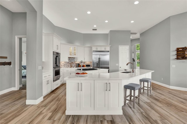 13112 Luntz Point Ln, Windermere, FL 34786 - kitchen with stainless steel appliances, a large island with sink, a sink, light wood-style flooring, and recessed lighting