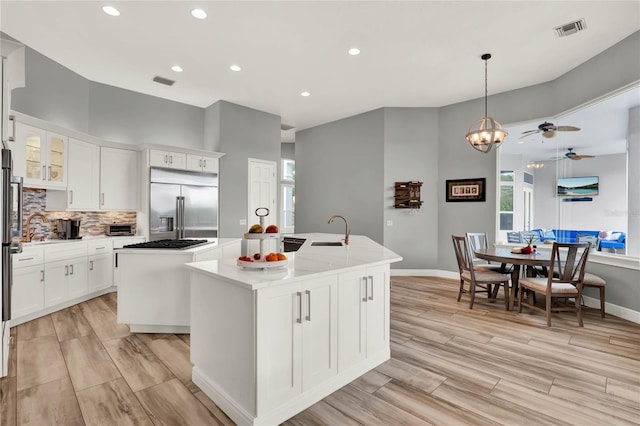 13112 Luntz Point Ln, Windermere, FL 34786 - kitchen with built in fridge, a kitchen island with sink, a sink, light wood finished floors, and baseboards