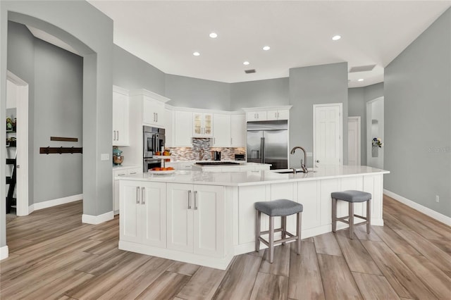 13112 Luntz Point Ln, Windermere, FL 34786 - kitchen with stainless steel appliances, a sink, light wood-type flooring, baseboards, and decorative backsplash
