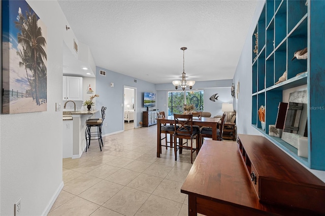 5300 S Atlantic Ave Unit 16-202, New Smyrna Beach, FL 32169 - dining area featuring an inviting chandelier, light tile patterned floors, a textured ceiling, and baseboards