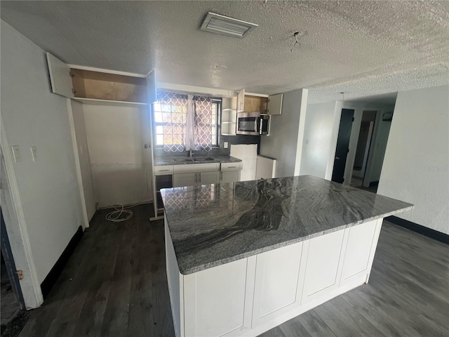 10228 Amadeus Dr, Port Richey, FL 34668 - kitchen featuring stainless steel microwave, dark wood-style flooring, a sink, and visible vents