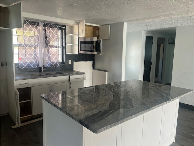 10228 Amadeus Dr, Port Richey, FL 34668 - kitchen with a sink, dark wood finished floors, a center island, stainless steel microwave, and dark stone counters