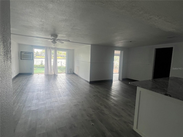 10228 Amadeus Dr, Port Richey, FL 34668 - unfurnished living room with a wall mounted AC, a textured ceiling, dark wood-style floors, baseboards, and ceiling fan