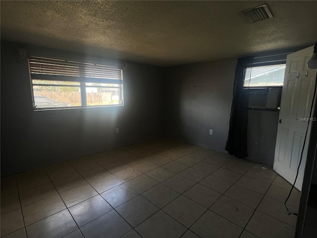 10228 Amadeus Dr, Port Richey, FL 34668 - spare room featuring a wealth of natural light, visible vents, tile patterned flooring, and a textured ceiling