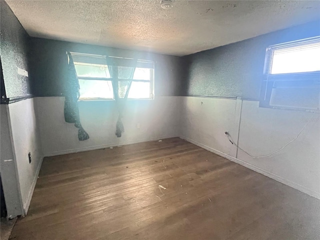 10228 Amadeus Dr, Port Richey, FL 34668 - empty room with a textured wall, a textured ceiling, and wood finished floors
