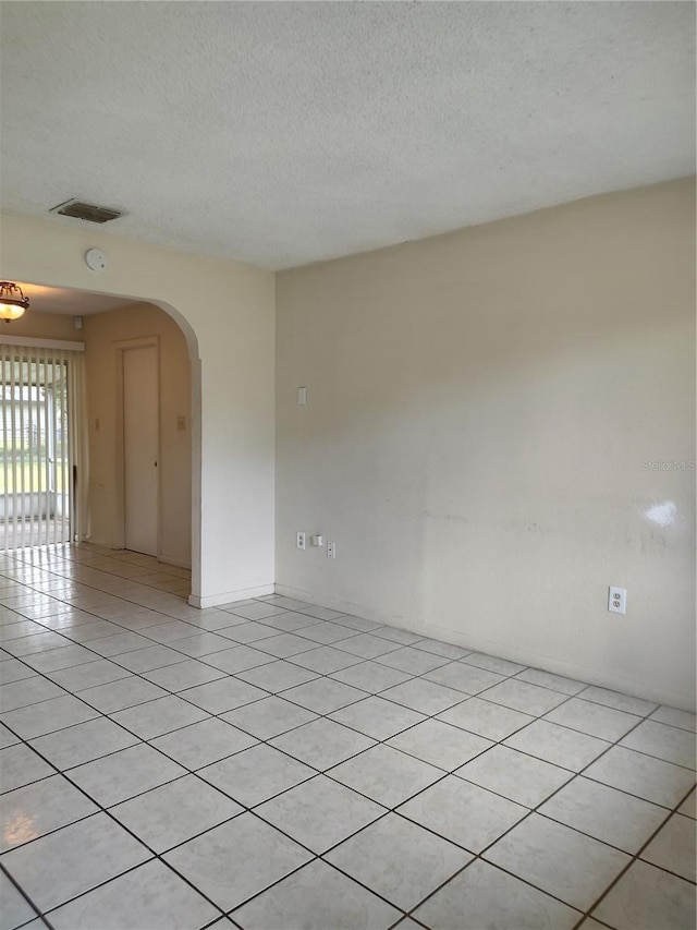 5177 Edwina St, Orlando, FL 32811 - spare room with arched walkways, a textured ceiling, visible vents, and light tile patterned flooring