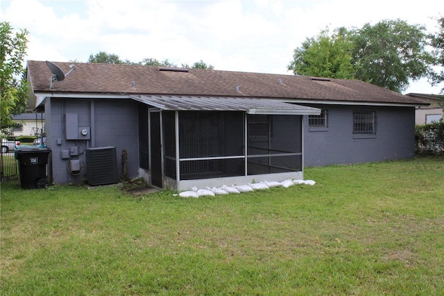 5177 Edwina St, Orlando, FL 32811 - back of house featuring roof with shingles, concrete block siding, a sunroom, central AC, and a yard