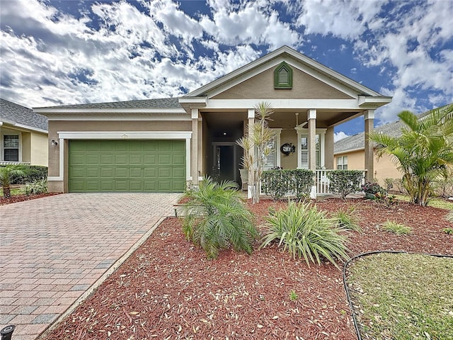 view of front facade with covered porch, a garage, decorative driveway, and stucco siding