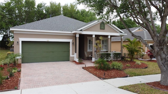 ranch-style home featuring stucco siding, covered porch, a shingled roof, and decorative driveway