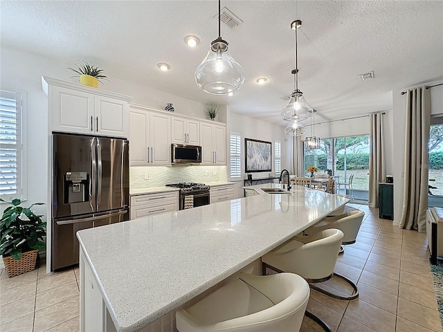 kitchen with decorative backsplash, visible vents, a sink, and stainless steel appliances