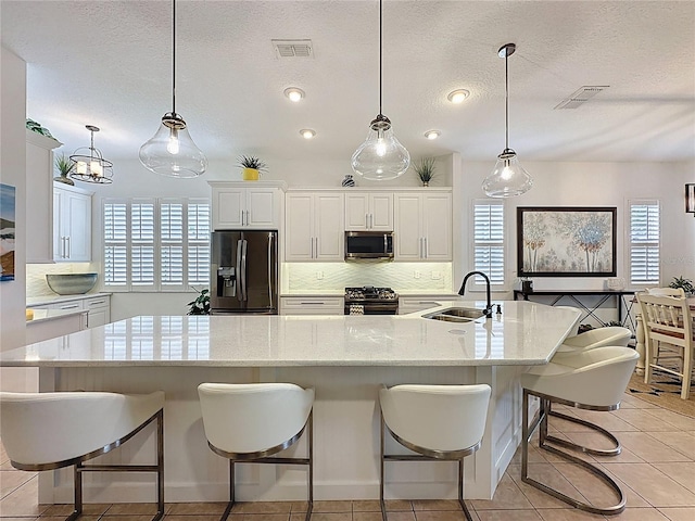 kitchen featuring visible vents, tasteful backsplash, a sink, and stainless steel appliances