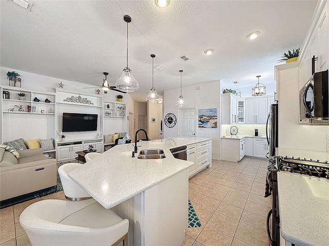 kitchen featuring a sink, black microwave, a spacious island, gas range, and fridge