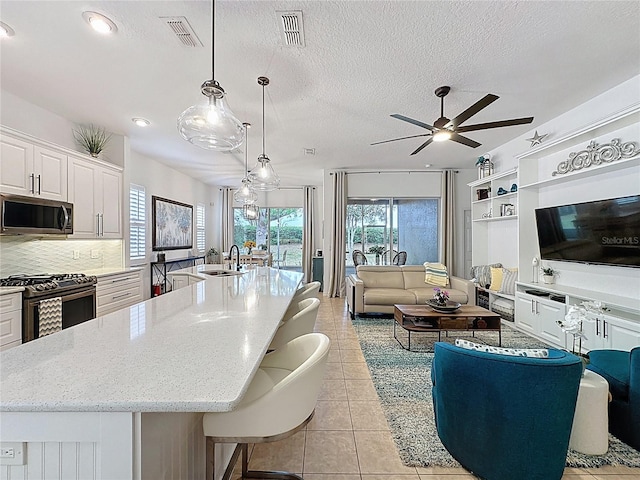 kitchen featuring visible vents, gas range oven, a sink, and stainless steel microwave