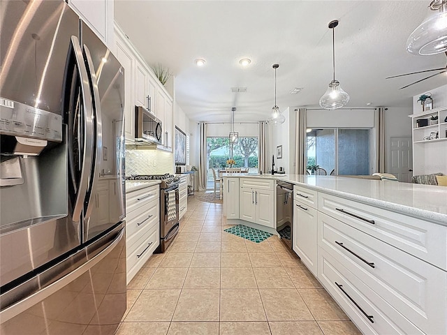 kitchen with backsplash, appliances with stainless steel finishes, hanging light fixtures, light tile patterned floors, and white cabinets