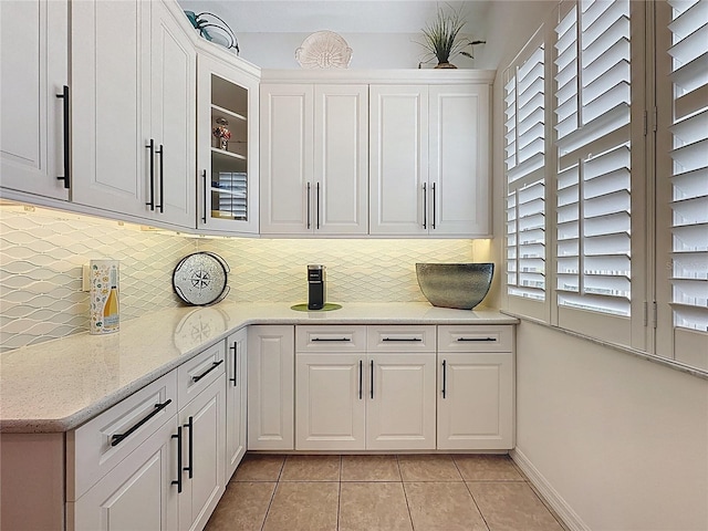 kitchen featuring decorative backsplash, glass insert cabinets, white cabinetry, and light tile patterned floors