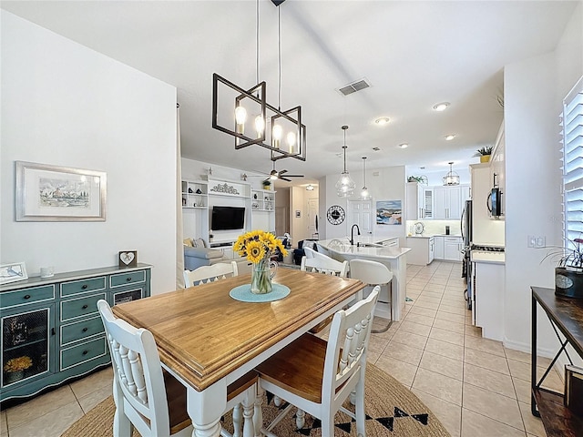 dining room with light tile patterned flooring, ceiling fan with notable chandelier, and visible vents