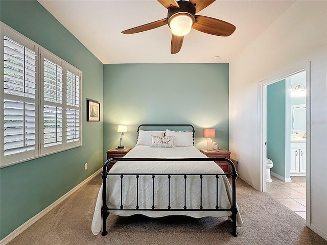 tiled bedroom featuring carpet flooring, ensuite bath, baseboards, and ceiling fan