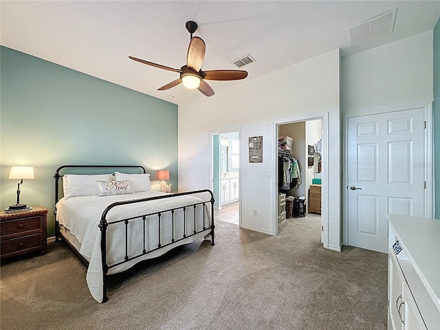 bedroom featuring a spacious closet, carpet flooring, ceiling fan, visible vents, and ensuite bathroom