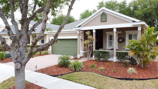 view of front facade with decorative driveway, stucco siding, an attached garage, and a porch