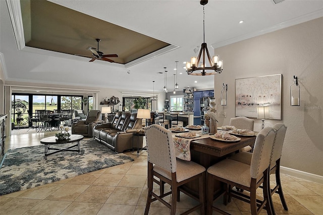 dining room featuring a tray ceiling, crown molding, ceiling fan with notable chandelier, baseboards, and light tile patterned flooring