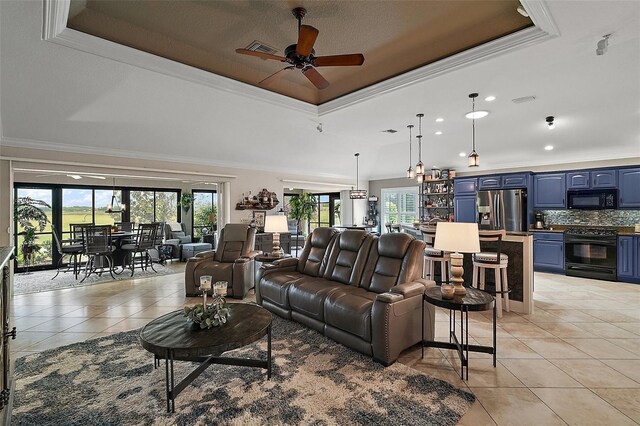 living room with ceiling fan, visible vents, crown molding, and a raised ceiling