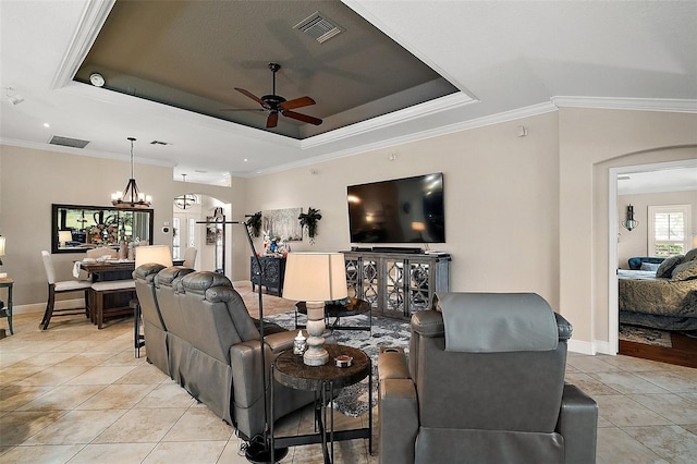 living area featuring a raised ceiling, arched walkways, ceiling fan with notable chandelier, and visible vents