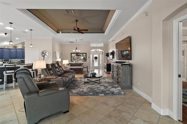 living area with a tray ceiling, light tile patterned floors, ceiling fan with notable chandelier, visible vents, and ornamental molding