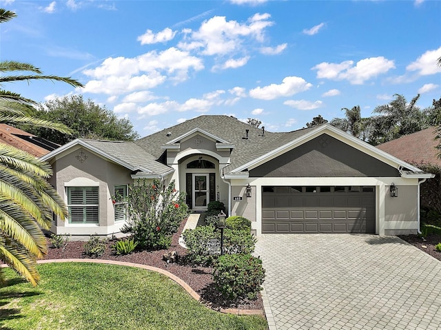 single story home featuring a garage, decorative driveway, and stucco siding