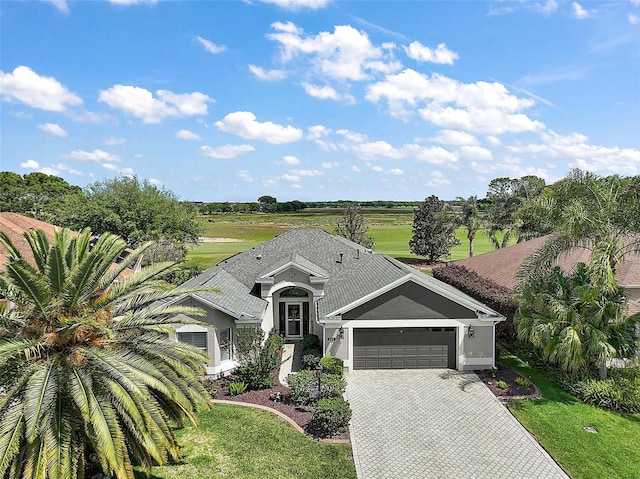 ranch-style house with a front lawn, decorative driveway, stucco siding, and an attached garage