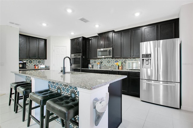 161 Williamson Dr, Davenport, FL 33897 - kitchen with stainless steel appliances, tasteful backsplash, a breakfast bar area, visible vents, and light stone countertops