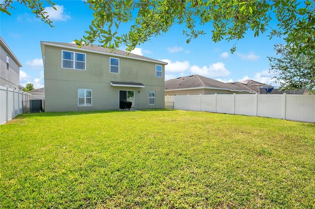 161 Williamson Dr, Davenport, FL 33897 - back of property with cooling unit, stucco siding, a lawn, and a fenced backyard