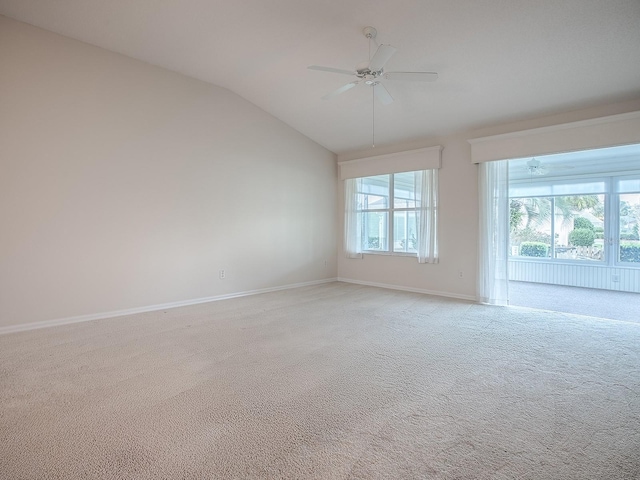 spare room featuring light colored carpet, lofted ceiling, ceiling fan, and baseboards