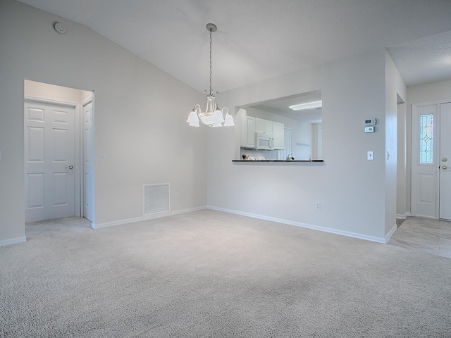 unfurnished dining area featuring lofted ceiling, baseboards, a chandelier, visible vents, and light carpet