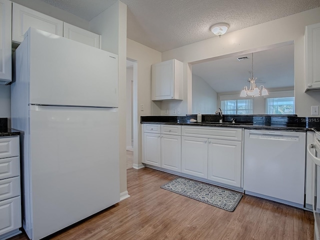 kitchen featuring white cabinetry, white appliances, a sink, light wood-style floors, and a notable chandelier