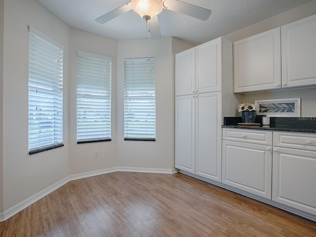 kitchen featuring a ceiling fan, white cabinets, a textured ceiling, and light wood-type flooring