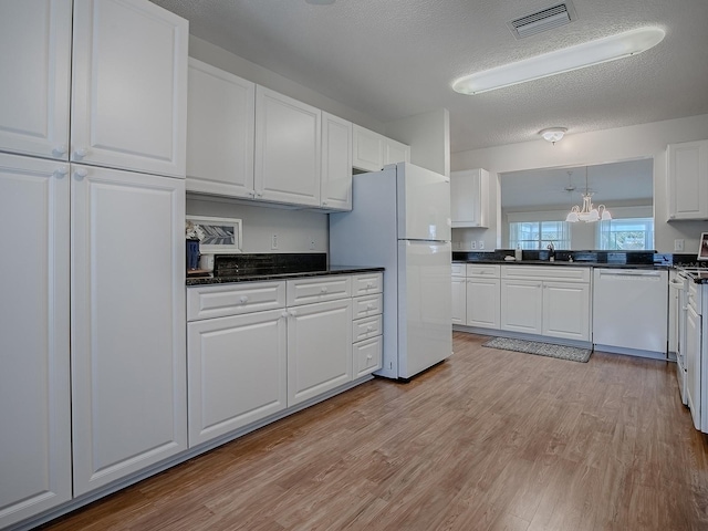 kitchen featuring white cabinetry, visible vents, dark countertops, and white appliances