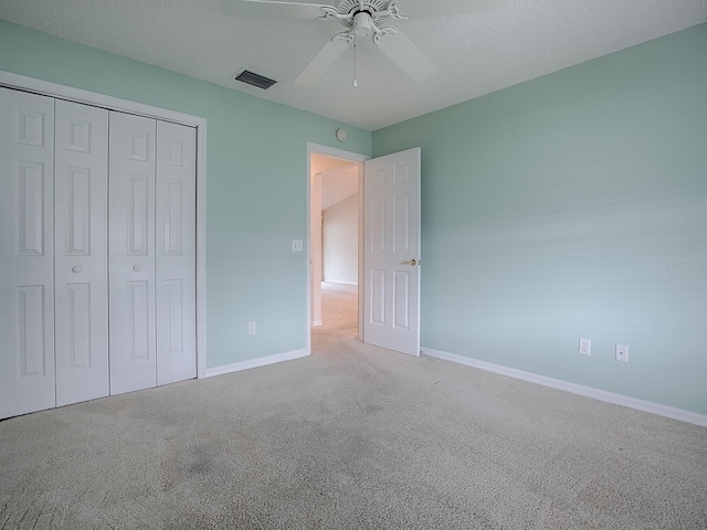 unfurnished bedroom with carpet flooring, baseboards, visible vents, a ceiling fan, and a closet