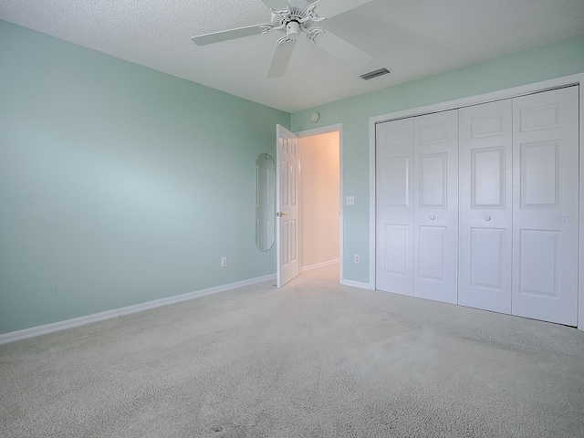 unfurnished bedroom featuring a closet, a textured ceiling, baseboards, visible vents, and carpet